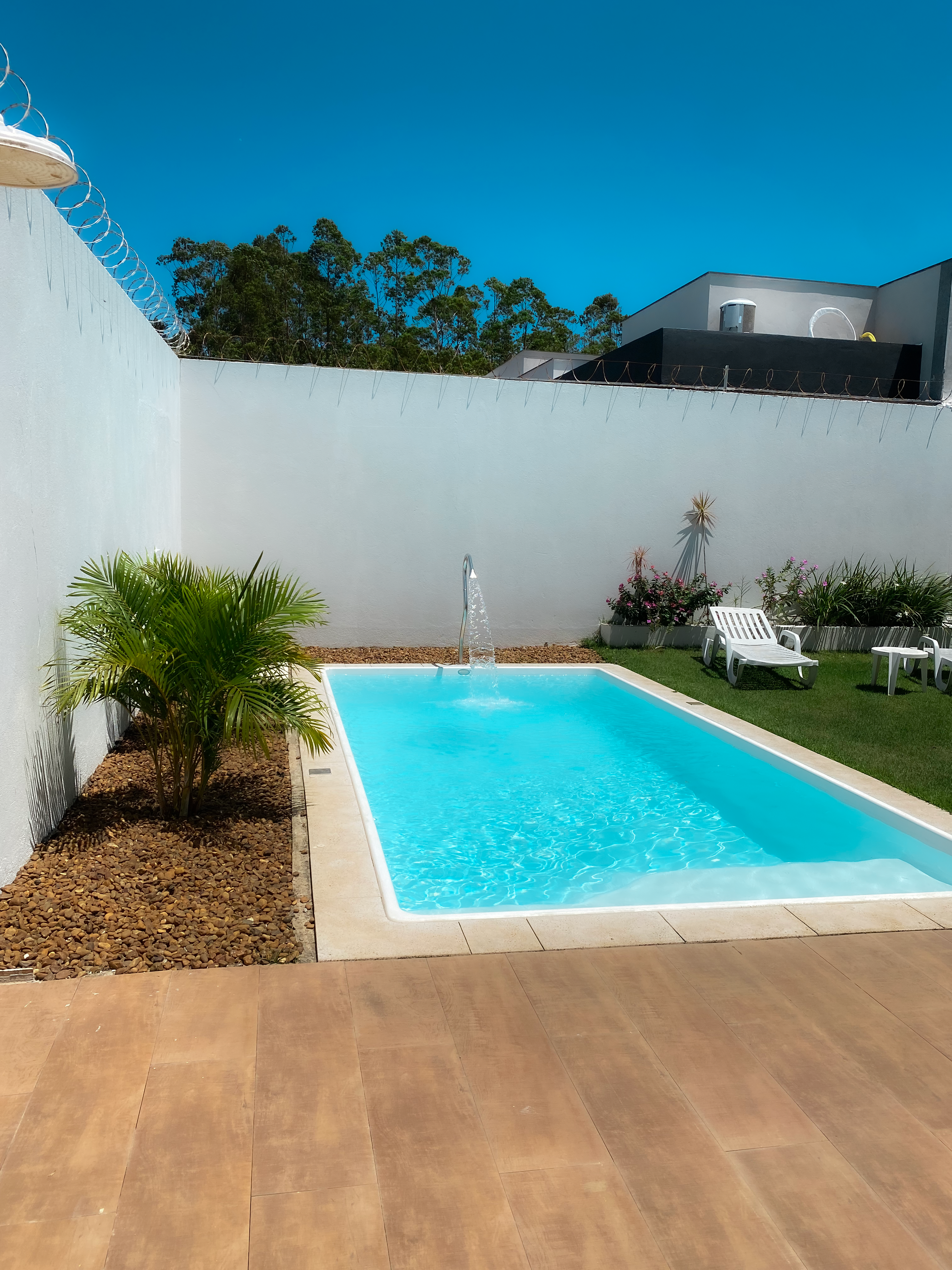 Piscina com cascata e área de sol.